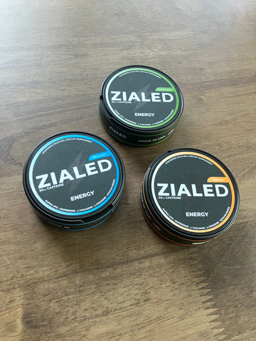 Fresh Mint, Wintergreen, and Tropical Zialed cans on a wooden table